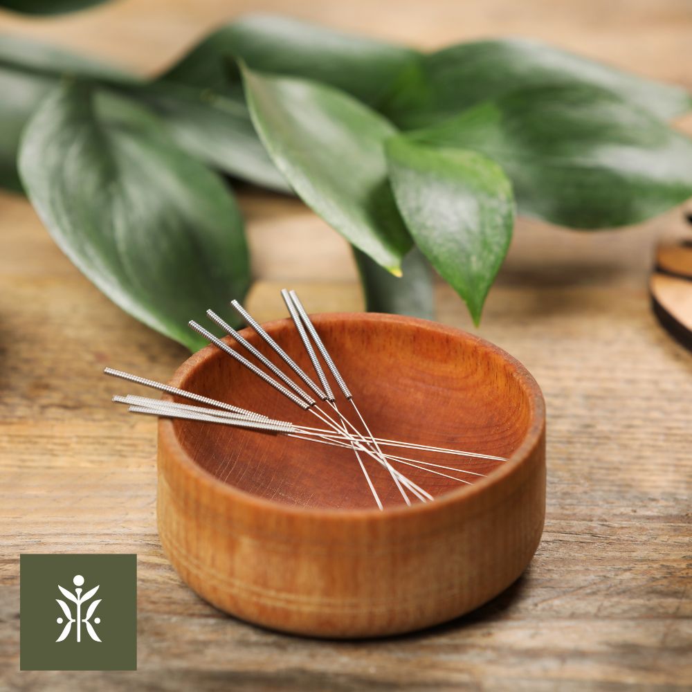 Acupuncture needled in a wooden pot with leaves resting behind it
